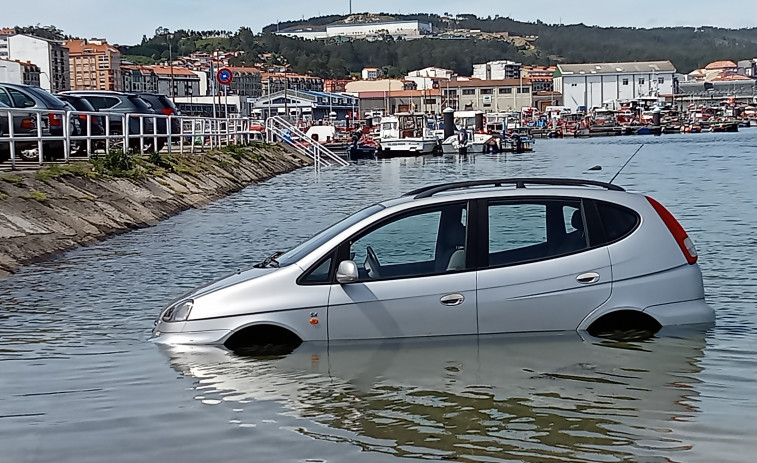 Un nuevo coche aparcado en la rampa de varada del puerto de Ribeira fue alcanzado por el agua al subir la marea