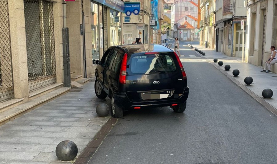 Un coche acaba subido a una bola metálica o bolardo en el casco urbano de Ribeira