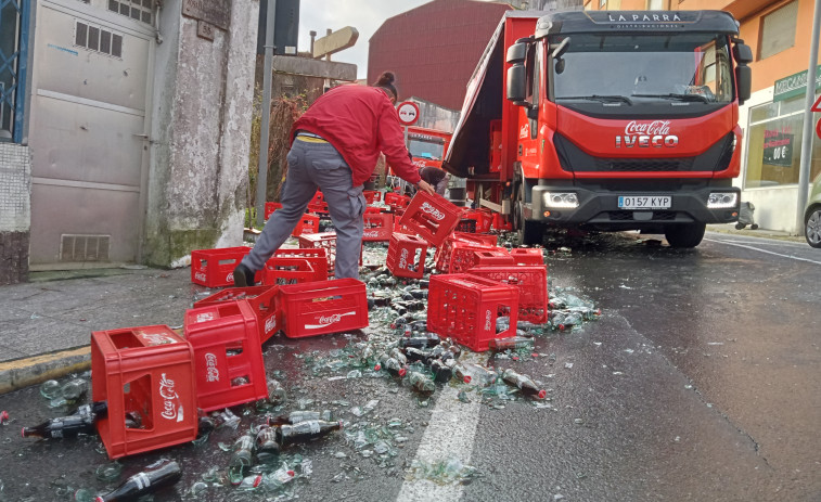 Un camión de reparto derrama gran parte de su carga de botellas de refrescos en un céntrico vial de Ribeira