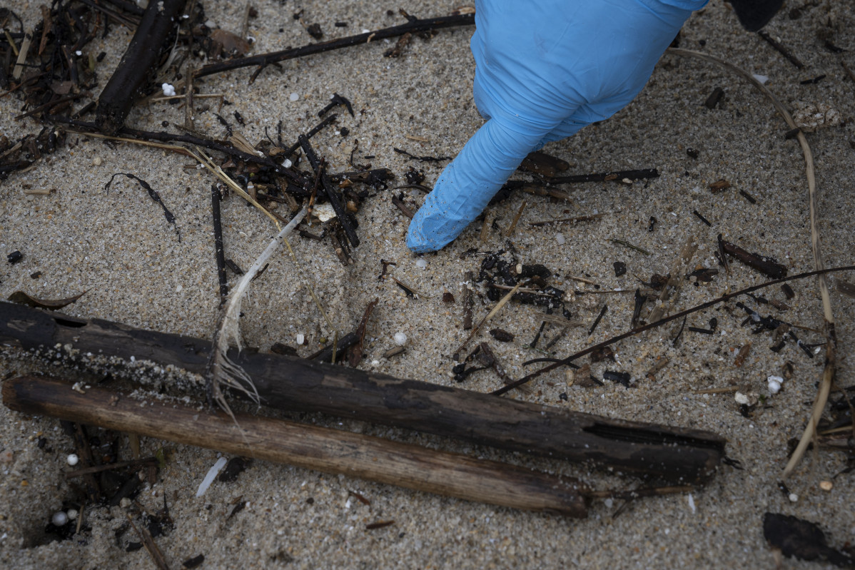 Un voluntario recoge pellets en la playa de Samil @ EP